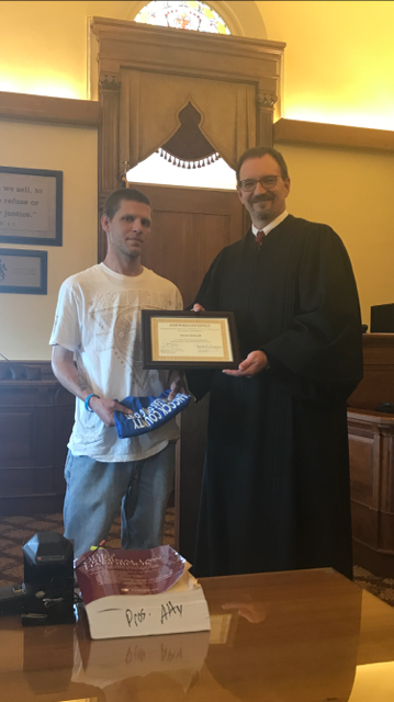 Judge handing young man certificate