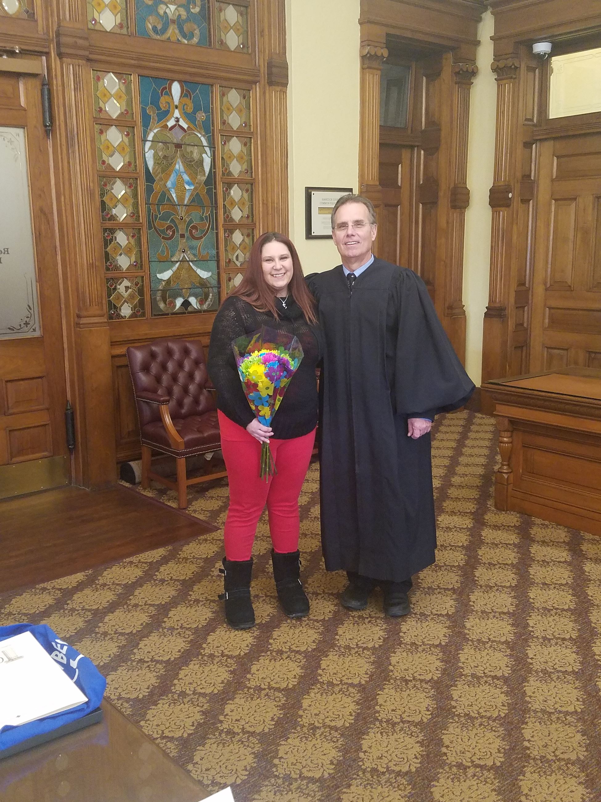 Lady holding flowers next to judge at graduation